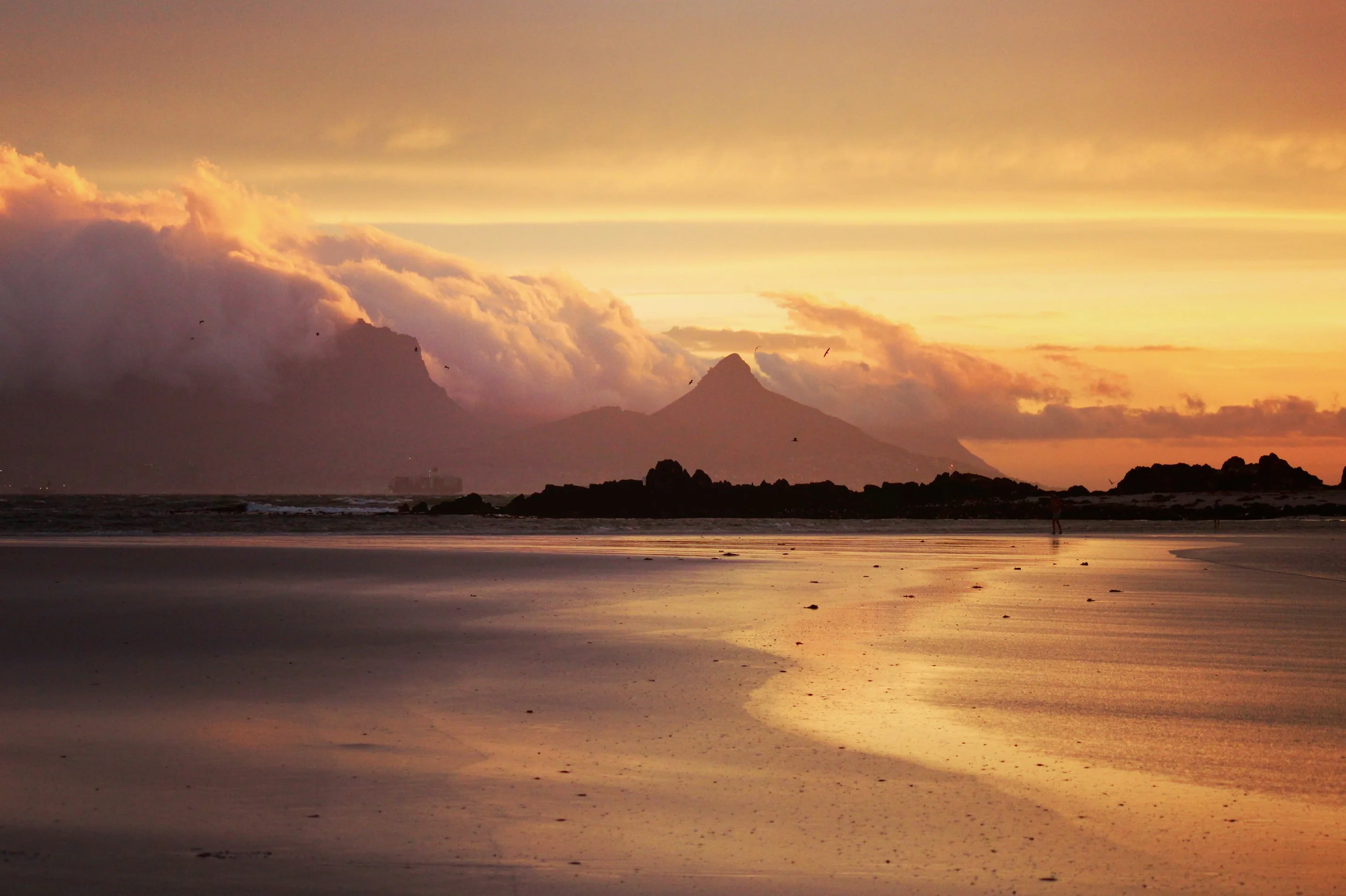 A beach at sunset beneath a mountain